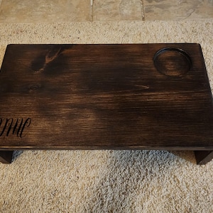 May include: A dark brown wooden tray with a small circular cutout for a cup or glass. The tray has a raised edge and is personalized with the initials "DMC".
