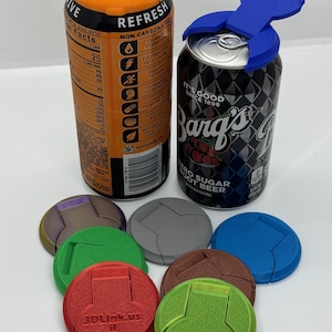 May include: An orange can of VIVE and a black can of Barq's Root Beer with a blue lid. Several colored can lids are displayed, including red, green, gray, and brown. The red lid has the text "3DLink.us R".