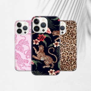May include: Three iPhone cases with different designs. The first case is pink with a white outline of a leopard print. The second case is black with a leopard print and tropical flowers. The third case is brown with a leopard print.