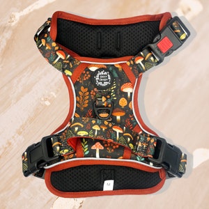 May include: Red and black dog harness with a mushroom and leaf pattern. The harness has a size label that says "M".