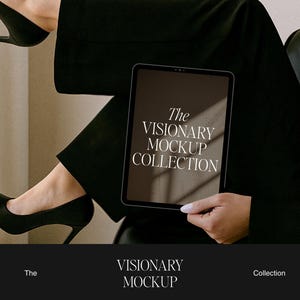 May include: A tablet displaying "The Visionary Mockup Collection" is held by a person wearing black heels and pants. The tablet has a dark screen with white text. The image has a neutral color palette.