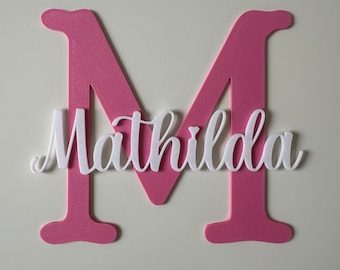 May include: Pink foam letter M with the name Matilda written in white foam letters on top.