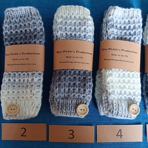 May include: Five hand-knitted leg warmers in grey and white, each with a wooden button and a brown paper band. The bands read "Miss Pickle's Productions Made in the UK". The leg warmers are numbered 1 to 5.
