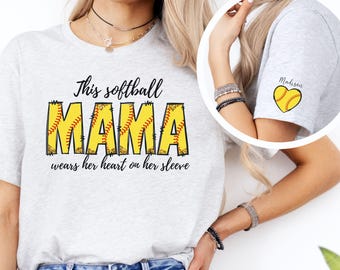 May include: Gray t-shirt with the text "This softball mama wears her heart on her sleeve" and a yellow softball graphic. The sleeve has a smaller yellow softball graphic with the text "Madison".