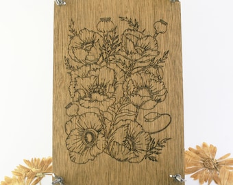 May include: A wooden plaque with a laser-etched design of a bouquet of poppies. The plaque is mounted on a white background with dried flowers scattered around it.