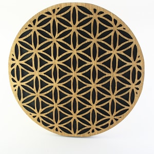 May include: A round wooden coaster with a black geometric pattern. The pattern is a repeating design of triangles and ovals.