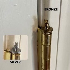 May include: Two door hinges with decorative cat toppers. The left hinge has a silver cat topper and the right hinge has a bronze cat topper. The word "SILVER" is below the left hinge and the word "BRONZE" is above the right hinge.