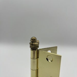 May include: A gold door hinge with a small gold duck figurine on top.
