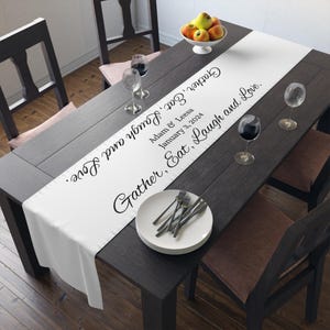 May include: White table runner with black text that reads "Gather, Eat, Laugh and Love."  The text also includes the names "Adam & Leesa" and the date "January 3, 2024".