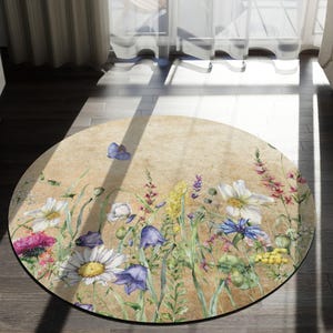 May include: A round rug with a floral design featuring a variety of flowers, including daisies, bluebells, and wildflowers. The rug has a beige background with a vintage, faded look.