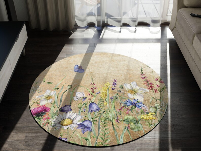 May include: A round rug with a floral design featuring a variety of flowers, including daisies, bluebells, and wildflowers. The rug has a beige background with a vintage, faded look.