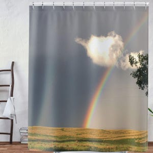 May include: A double rainbow arches over a field of golden grass with a single white cloud in the sky.