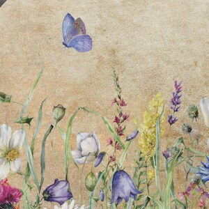 May include: A watercolour painting of a round floral arrangement with a light brown background. The arrangement features a variety of flowers, including white daisies, purple bellflowers, blue cornflowers, and yellow wildflowers. A single blue butterfly is flying above the flowers.