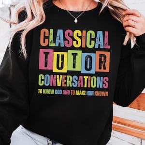 May include: Black sweatshirt with the text "CLASSICAL TUTOR CONVERSATIONS" in colorful block letters. The text "TO KNOW GOD AND TO MAKE HIM KNOWN" is below the main text. The sweatshirt is a casual style.