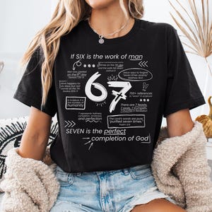 May include: Black t-shirt with white text. The shirt features the text "If SIX is the work of man" and "SEVEN is the perfect completion of God". The number 67 is prominently displayed, along with other related text.