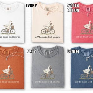 Puede incluir: Seis camisetas en blanco, marfil, sand&iacute;a, &ntilde;ame, gris y denim. Cada camiseta presenta un dibujo de un ganso en bicicleta con una cesta y el texto "off to make God known".