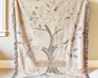 May include: A beige family tree throw blanket with a fringed edge. The tree design features heart-shaped leaves with names like "Madelyn Rae Johnson" and "February 13, 2020." The blanket has a woodland theme with foxes and rabbits.
