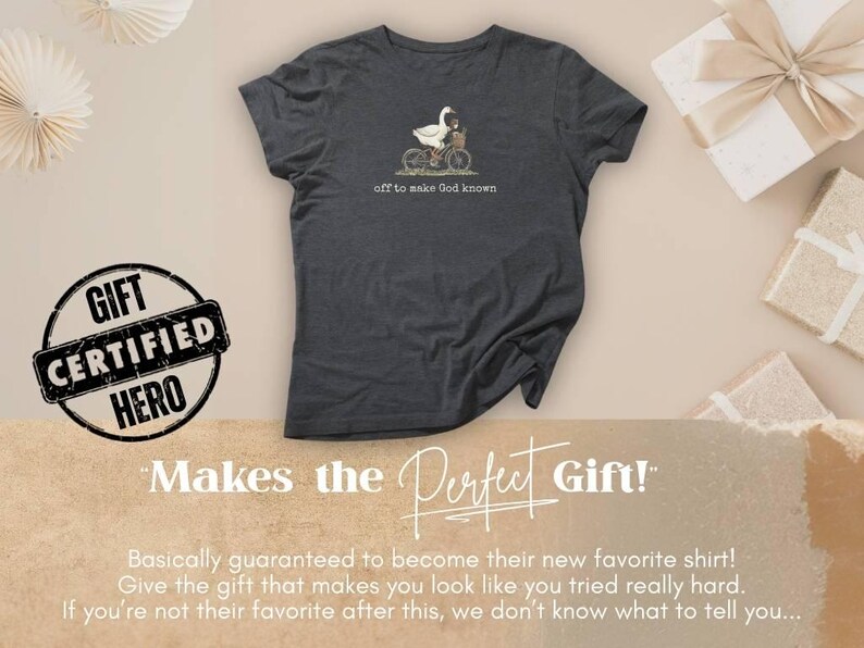 Puede incluir: Camiseta gris oscuro con un ganso en bicicleta y el texto "off to make God known". La imagen incluye cajas de regalo y decoraciones de papel. Una insignia dice "Gift Certified Hero".