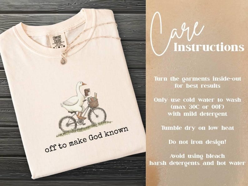 Puede incluir: Camiseta color crema con una ilustraci&oacute;n de un ganso en bicicleta y el texto "off to make God known". Tambi&eacute;n se ven las instrucciones de cuidado. La camiseta est&aacute; doblada sobre una superficie de madera oscura.