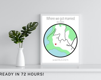 Può includere: Stampa incorniciata con un contorno di mappa e un cuore che indica una posizione. Il testo "Where we got married 8.4.2023" è sopra, con le coordinate sotto. Un vaso bianco con foglie verdi a sinistra.
