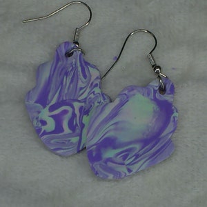 Peut inclure: Une paire de boucles d'oreilles pendantes marbrées de couleur pourpre et blanche avec des crochets argentés.