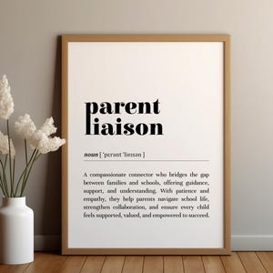 May include: A framed print with the words "parent liaison" in bold black font. The definition below describes the role of a compassionate connector between families and schools. A white vase with white flowers is on the left.