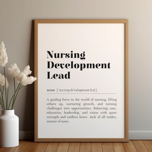 May include: A framed print with the words "Nursing Development Lead" in bold black font. The definition of the term is below the title. A white vase with white flowers is to the left of the print.