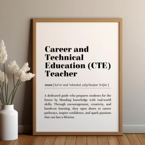 Może przedstawiać: Oprawiony wydruk z tekstem "Career and Technical Education (CTE) Teacher" czcionką pogrubioną. Wydruk jest w jasnobrązowej ramie i obok białego wazonu z białymi kwiatami.