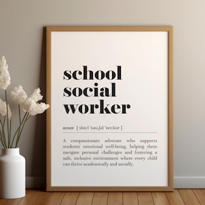 May include: A framed print with the words "school social worker" in bold black font. Below the title is the definition of a school social worker. A white vase with white flowers sits in front of the print.