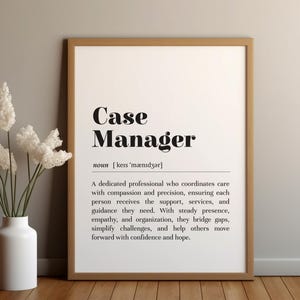 Puede incluir: Impresión enmarcada con las palabras "Case Manager" en negro, seguida de una definición. Un jarrón blanco con flores blancas está a la izquierda del marco. El marco es marrón, sobre un fondo gris claro.