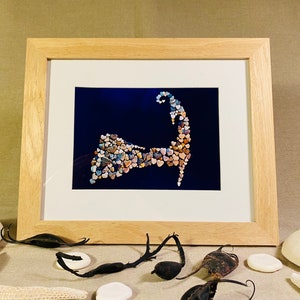 May include: A framed print of the Cape Cod coastline, created with small, colorful stones on a dark blue background.