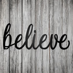 Könnte beinhalten: Schwarze Wanddekoration aus Metall mit dem Wort "glauben" in einer kursivschriftlichen Schriftart. Die Dekoration ist auf einem Holzgrund montiert.