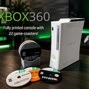 Może przedstawiać: Biała konsola Xbox 360 z zestawem podkładek pod kubki z motywem gier. Podkładki prezentują tytuły gier takie jak "Call of Duty" i "Oblivion". Obraz zawiera tekst "XBOX360" i "Fully printed console with 22 game-coasters!"