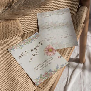 May include: Two cream-colored cards with floral borders and the words "date night jar." One card features a large pink flower. The text reads "Please leave your best date night ideas for the happy couple."