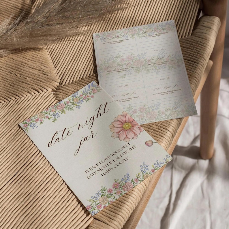 May include: Two cream-colored cards with floral borders and the words "date night jar." One card features a large pink flower. The text reads "Please leave your best date night ideas for the happy couple."