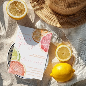 Puede incluir: Una invitación a una despedida de soltera con ilustraciones de acuarela de cítricos, incluyendo limones, pomelos y naranjas. El texto de la invitación dice "Ella encontró a su amor principal" e incluye los detalles del evento. Un sombrero de paja y limones en rodajas están dispuestos alrededor de la invitación.