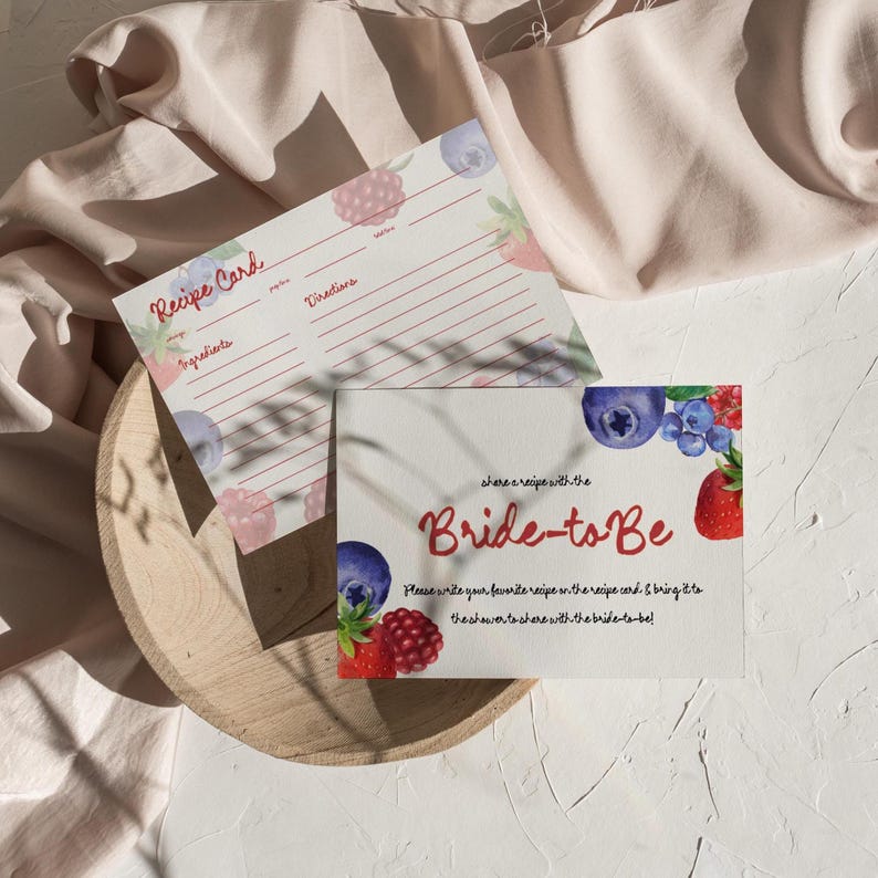 May include: Two white recipe cards with watercolor berry illustrations. One card reads "Recipe Card" and has lines for ingredients and directions. The other card says "Bride-to-Be" in red script and invites guests to share recipes.