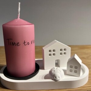 Può includere: Un vassoio in ceramica bianca con due piccole casette bianche e una candela rosa. La candela ha la scritta "Time to relax".