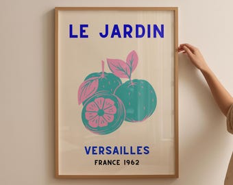 May include: Framed art print featuring a stylized illustration of green and pink citrus fruits with leaves. The text "LE JARDIN VERSAILLES FRANCE 1962" is printed in blue. The artwork is in a wooden frame.