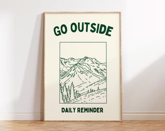 May include: Framed art print with a cream background and a green mountain illustration. The text "GO OUTSIDE" is at the top, and "DAILY REMINDER" is at the bottom. The artwork is in a wooden frame.