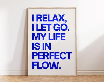 May include: A framed poster with the words "I RELAX, I LET GO. MY LIFE IS IN PERFECT FLOW" in bold blue letters. The poster is set against a white wall and rests on a wooden floor.