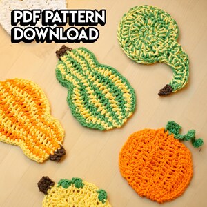 May include: A collection of handmade crochet pumpkin and gourd-shaped coasters in various colors, including orange, yellow, and green. The coasters have brown stems and green leaves. The text "PDF PATTERN DOWNLOAD" is in the upper left corner.