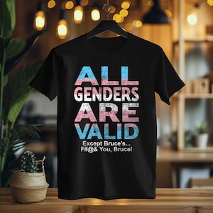 May include: Black t-shirt with the text "ALL GENDERS ARE VALID" in pink, blue, and white. The text "Except Bruce's... F#@& You, Bruce!" is printed below in white.