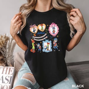 May include: Black crew neck t-shirt with a colourful Zootopia cartoon design. The graphic includes framed character images, the word "Zootopia", and decorative elements. The shirt is a casual style.