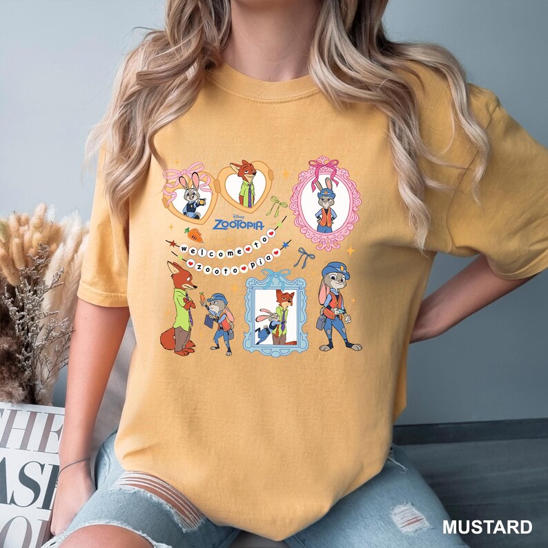 May include: Mustard-coloured t-shirt featuring cartoon characters from the film Zootopia. The design includes framed images of the characters, the film title, and the phrase "welcome to zootopia".
