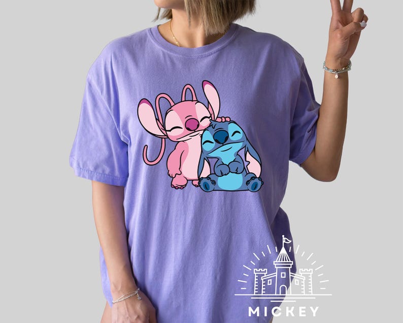 May include: Purple t-shirt with a pink and blue Stitch and Angel graphic. The graphic shows Stitch hugging Angel. The shirt has the text "MICKEY" printed on the bottom.