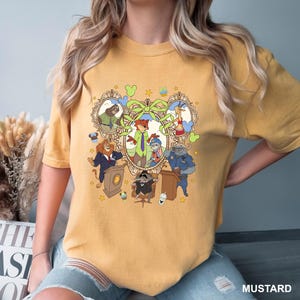 May include: Mustard-colored t-shirt featuring a cartoon graphic of characters from a popular animated movie. The graphic includes a fox, a bunny, a lion, and other animal characters. The word "MUSTARD" is printed at the bottom right.