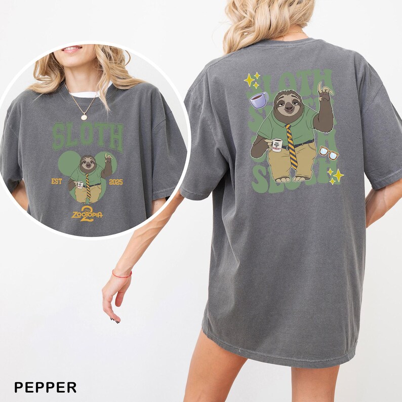 May include: A gray t-shirt featuring a cartoon sloth character from Zootopia 2. The sloth is wearing a green shirt, tie, and khaki pants, holding a coffee cup. The text "SLOTH" and "ZOOTOPIA 2" are also printed on the shirt.