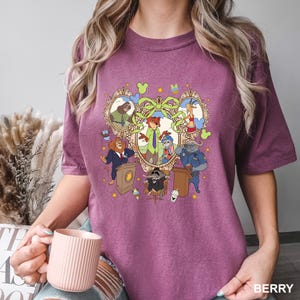 May include: Berry-colored t-shirt featuring a cartoon graphic of various animal characters in a decorative frame. The design includes a fox, bunny, lion, and other animals. The word "BERRY" is printed at the bottom right.