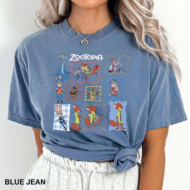 May include: Blue jean colored t-shirt featuring the word "Zootopia" above a grid of cartoon character illustrations. The shirt has short sleeves and a crew neck. The text "BLUE JEAN" is printed at the bottom.